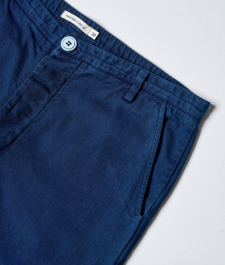 Flat lay image of a pair of navy blue chino-style pants with button closure and label tag - Industry of All Nations