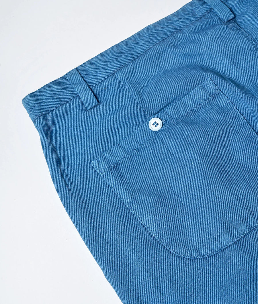 Flat lay of a pair of teal blue chino pants with a buttoned back pocket - Industry of All Nations