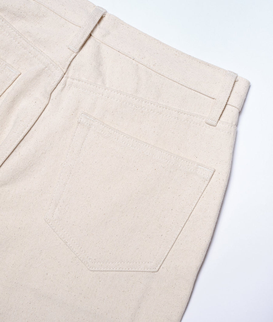 Detail shot of a natural beige cotton work pant with a pocket, displayed flat - Industry of All Nations