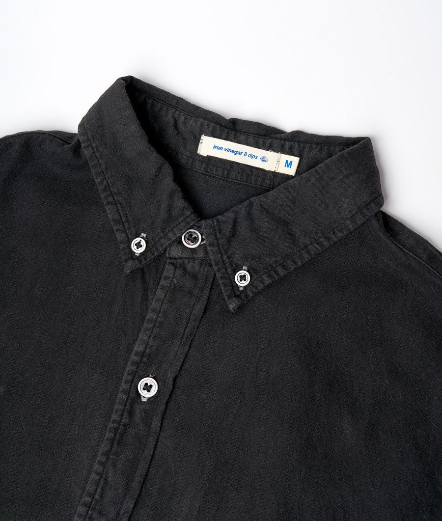 Flat lay detail shot of a black organic cotton button-down shirt by Industry of All Nations.