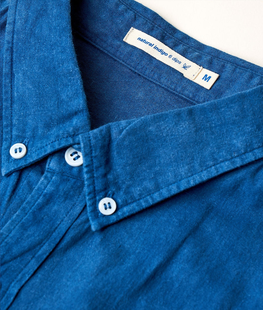 Close-up detail shot of a blue denim button-down shirt with natural indigo dye and a tag that reads "Natural Indigo 6 dips" - Industry of All Nations