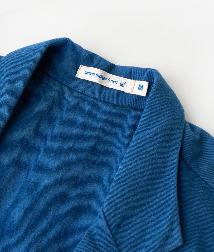 Close-up of a blue cotton jacket with a label that says "natural indigo 6 dips" - Industry of All Nations