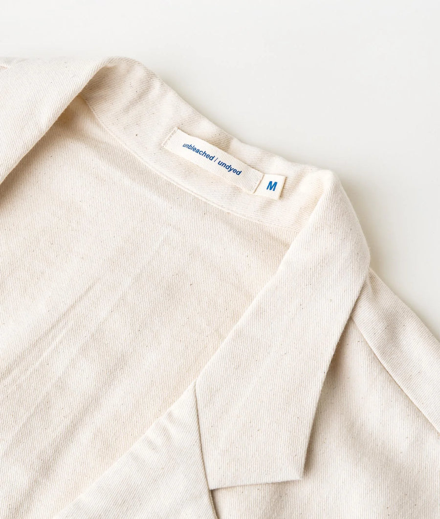 Flat lay image of a medium-sized, unbleached and undyed cotton t-shirt with a blue size tag - Industry of All Nations