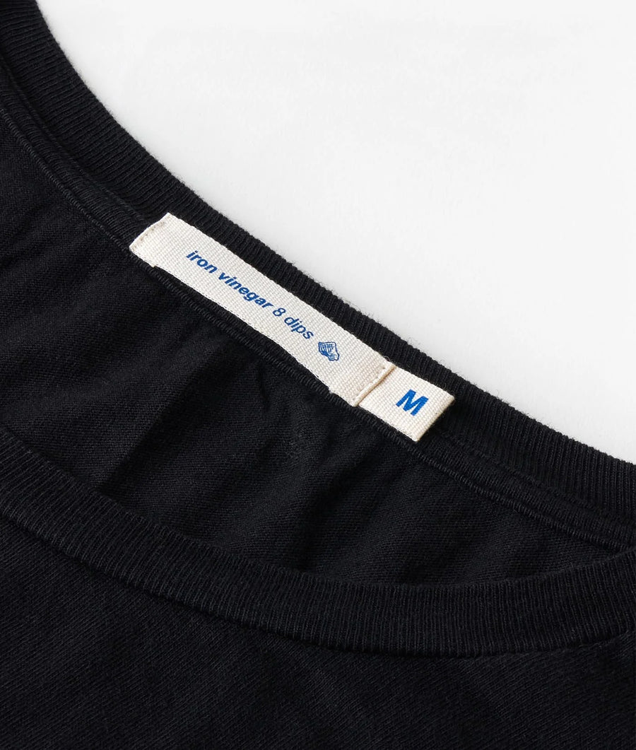 Detail shot of a black t-shirt with 'Iron vinegar & aloe' label - Industry of All Nations