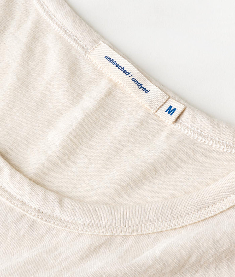 Closeup detail shot of a white organic cotton t-shirt with "Untbleached Unblocked" text and size M tag - Industry of All Nations