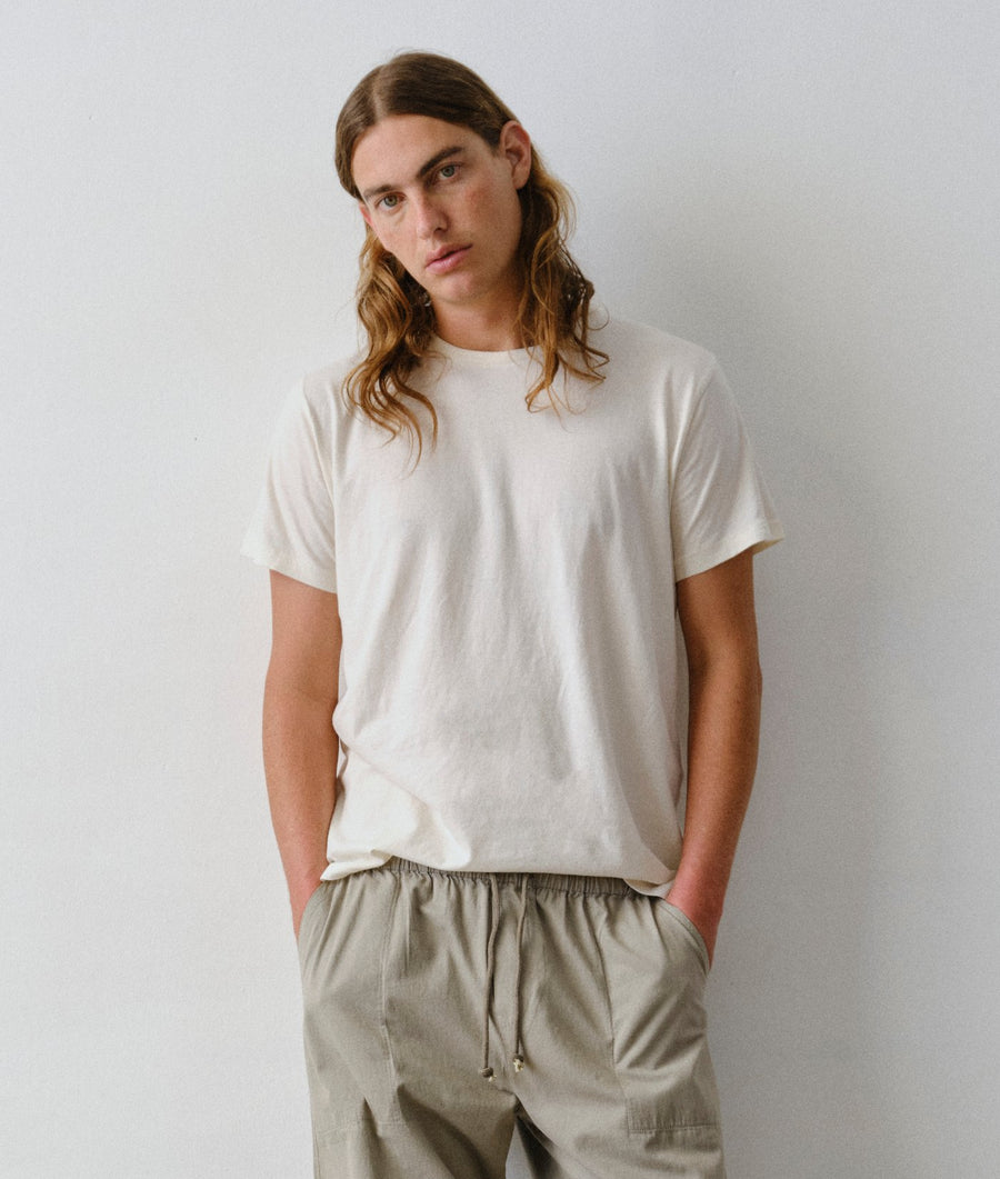 A man wearing an IOAN undyed short-sleeve Clean Crewneck T-shirt and matching IOAN Ponya Pants in Iron 4.