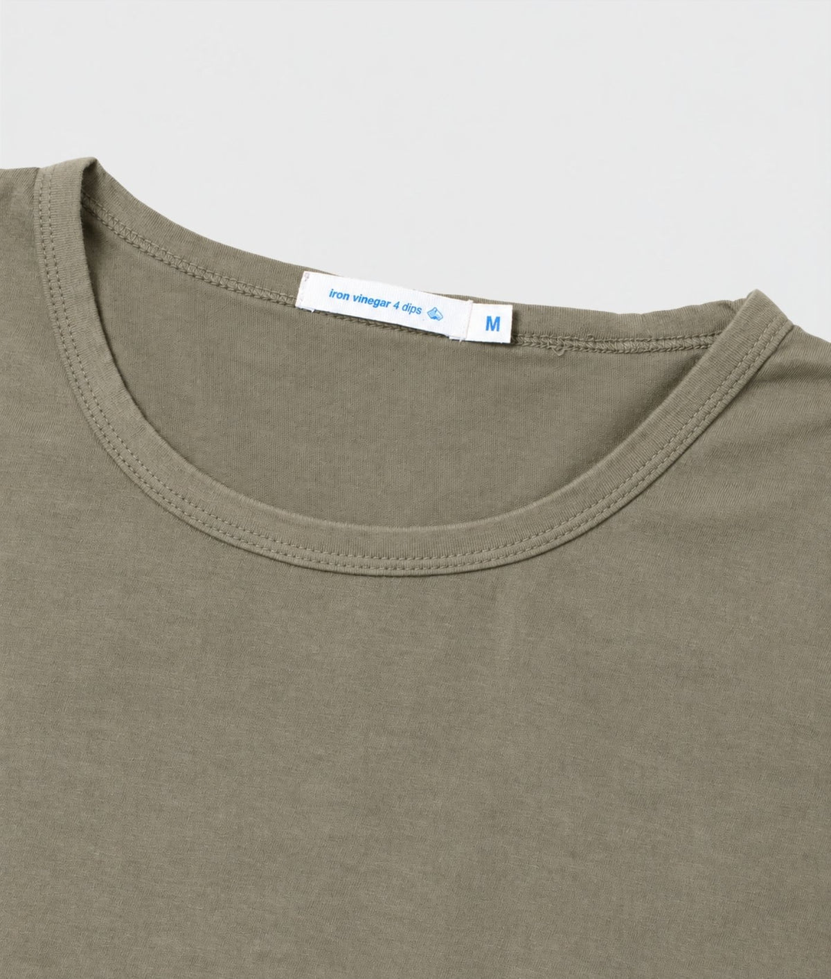 Close-up of a crew-neck t-shirt in olive green, showing the inner neck label with size 'M' and '100% vinger 4-pads'.
