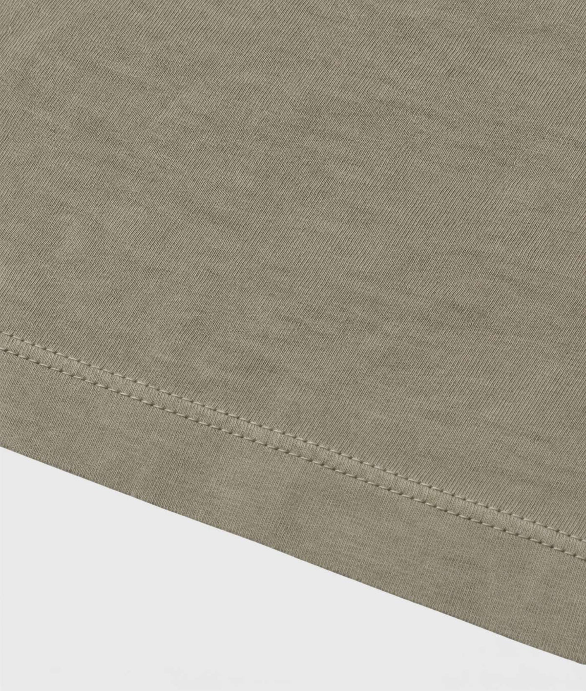 Close-up of a light taupe-beige knit fabric with a clean hemmed edge and visible stitching, shown against a white background.