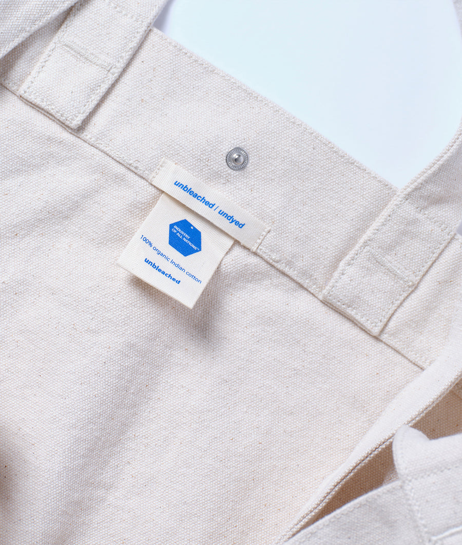 Close-up detail shot of a light-colored cotton garment with an unbleached label - Industry of All Nations