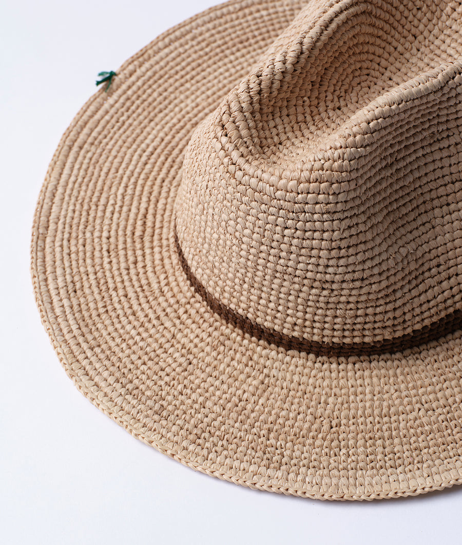 Close-up of a natural tan, woven straw sun hat with a green accent - Industry of All Nations