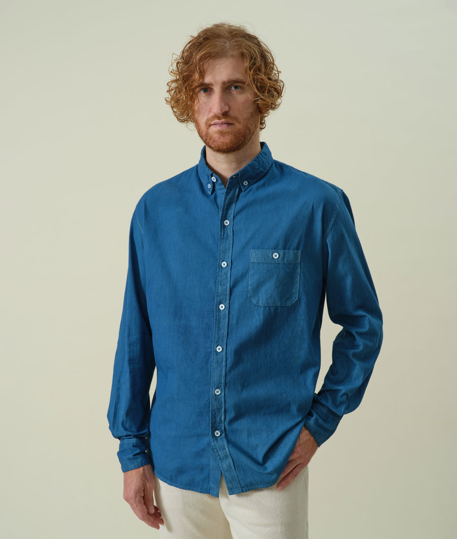 A man wearing a blue cotton button-down shirt in a portrait shot - Industry of All Nations