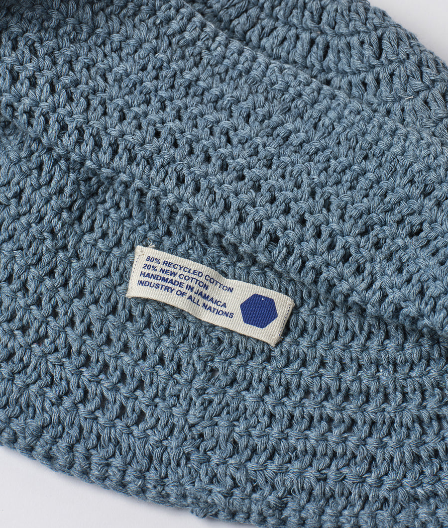 A close-up detail shot of a gray crocheted hat with a label that reads "80% recycled cotton, 20% new cotton. Handmade in Uruguay" - Industry of All Nations