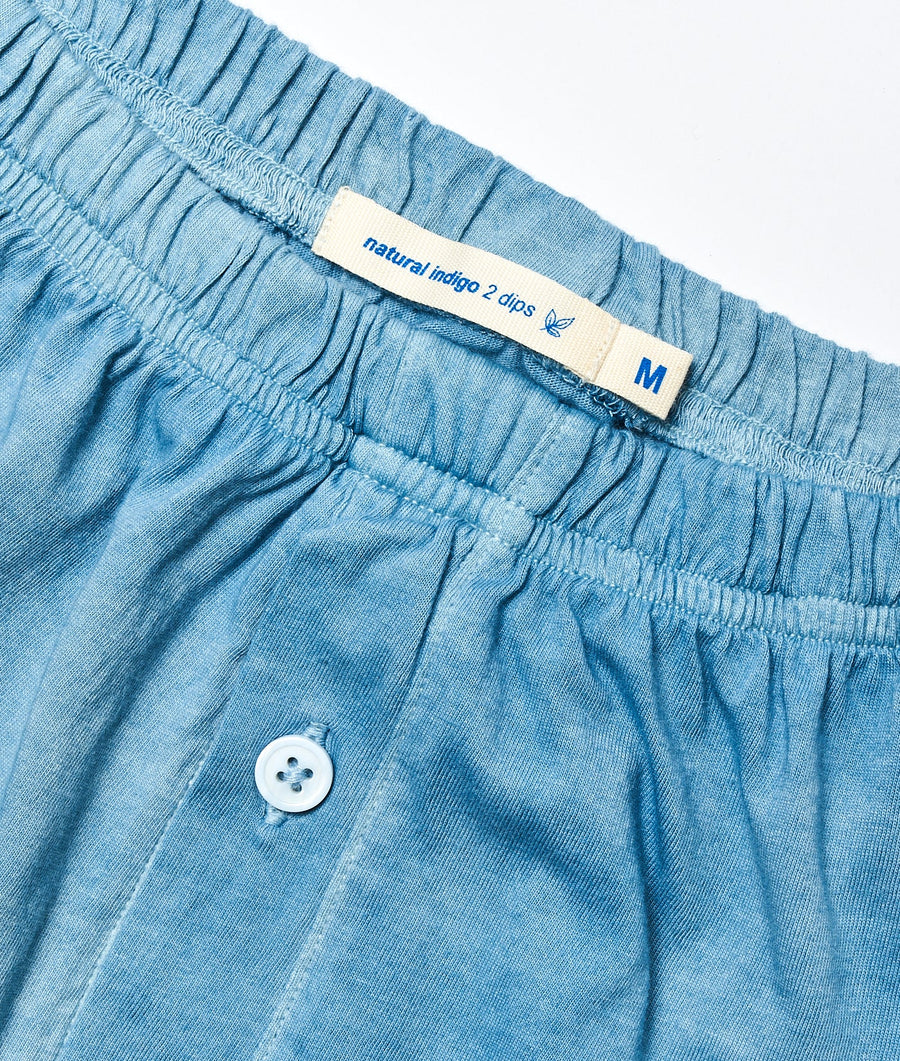 Close-up detail shot of a pair of light blue cotton shorts with a "natural indigo 2 dips" label - Industry of All Nations