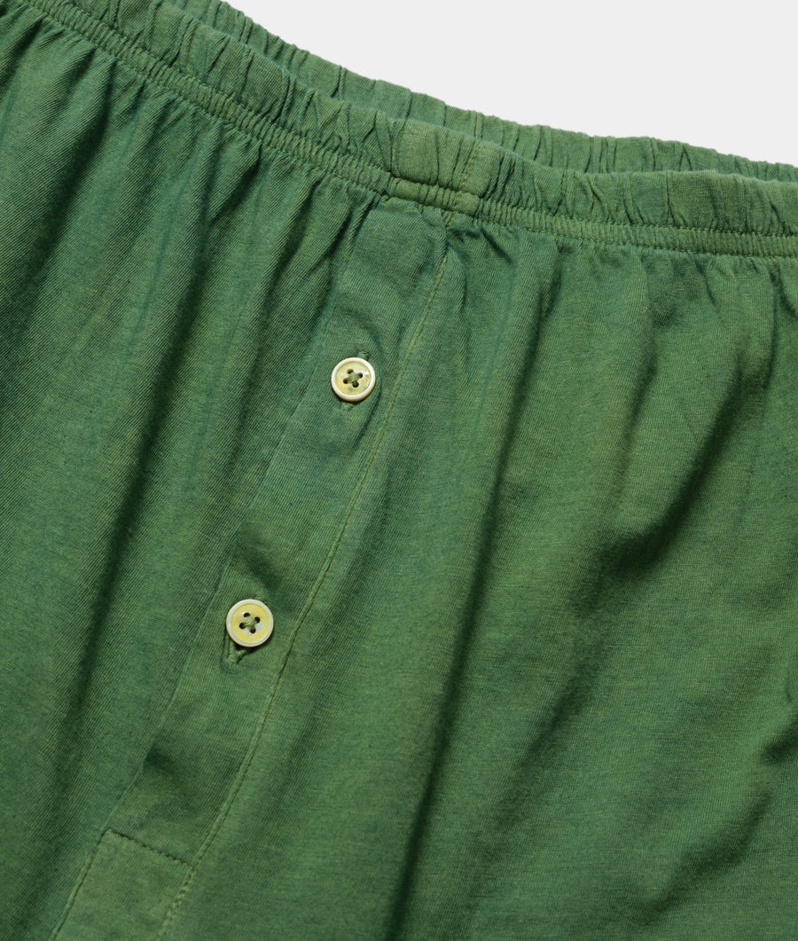 A close-up detail shot of a pair of green cotton drawstring shorts with tan buttons - Industry of All Nations