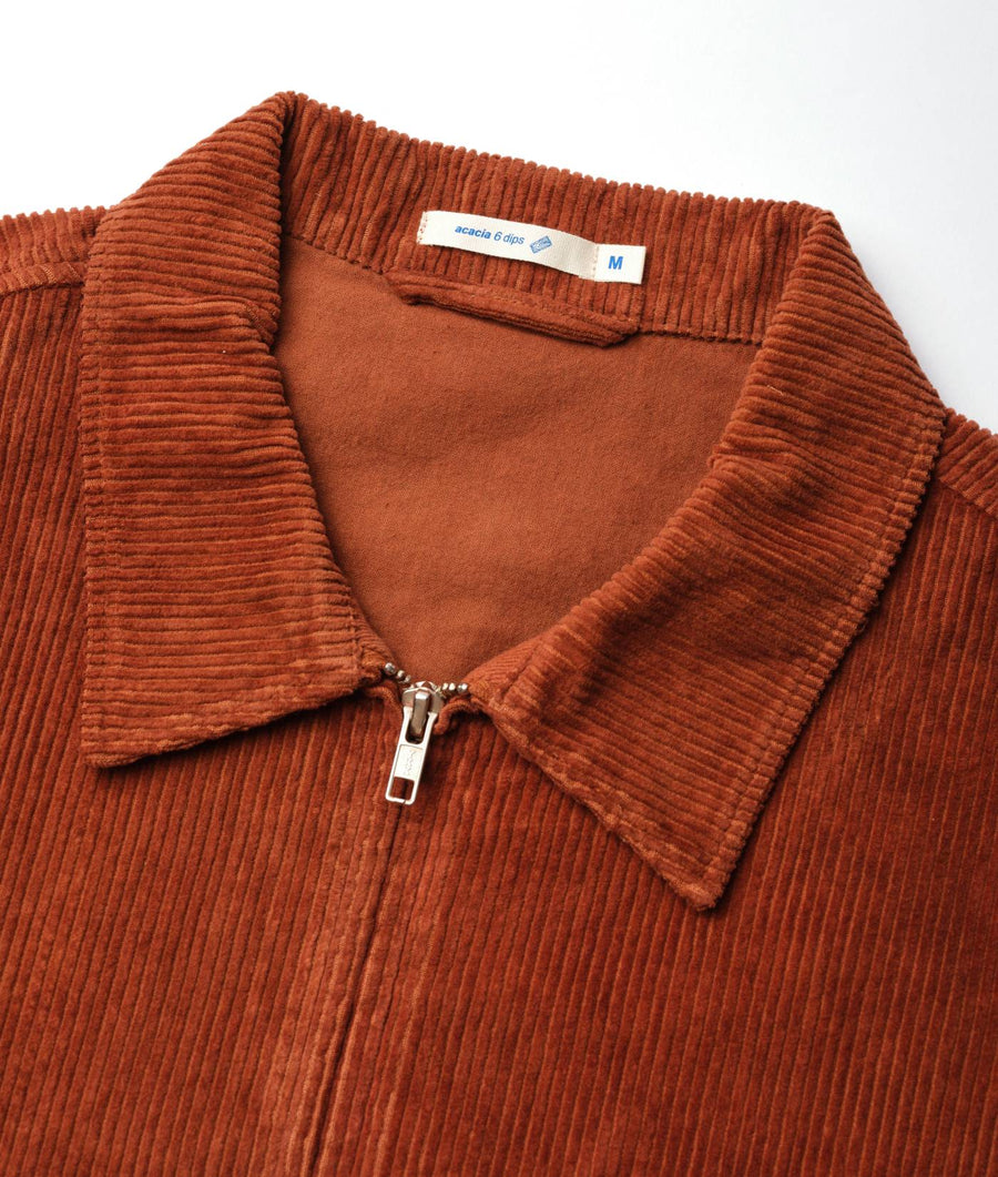 Rust-colored corduroy jacket with a zipper closure, displayed in a flat lay - Industry of All Nations