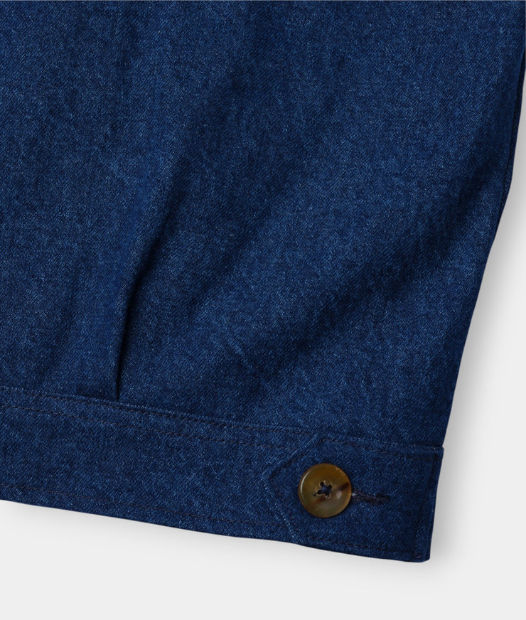 A close-up detail shot of a dark blue denim fabric with a brown button visible - Industry of All Nations