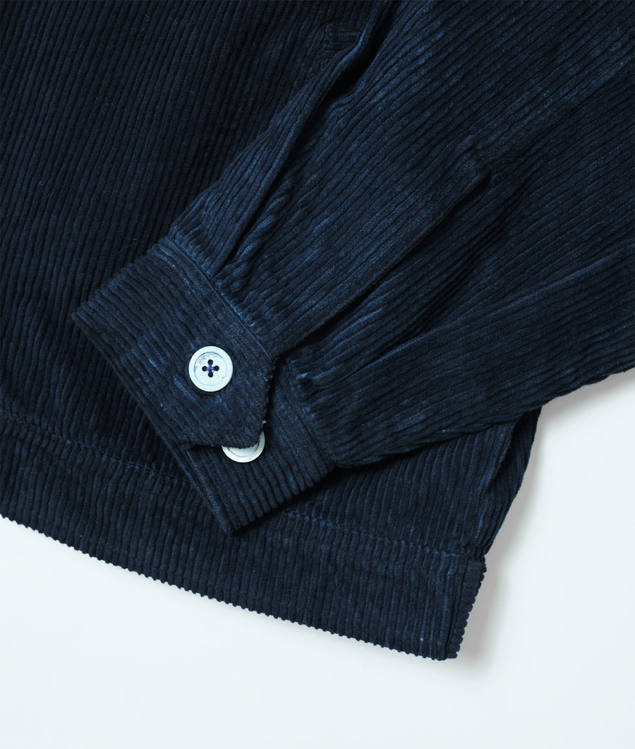 A close-up detail shot of the sleeve and button of a black organic cotton corduroy shirt - Industry of All Nations
