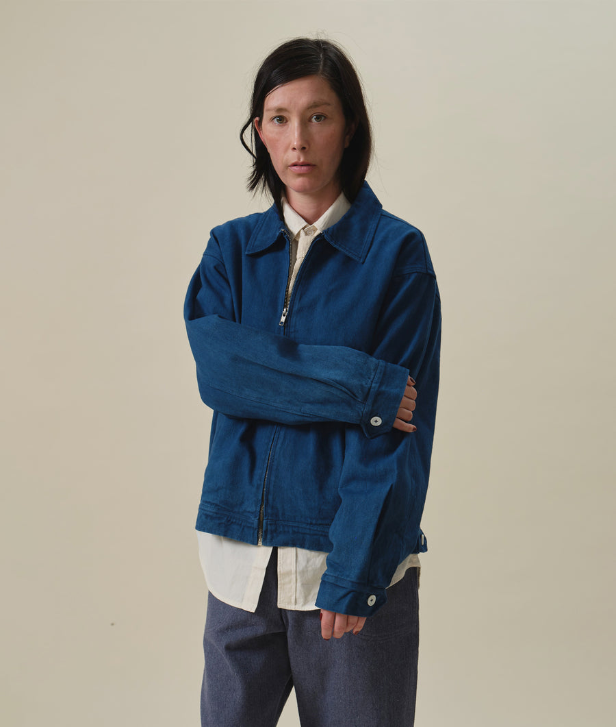 Blue denim jacket with zip closure, worn by a woman with short dark hair against a neutral background - Industry of All Nations