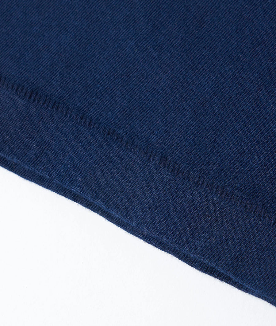 Close-up view of a navy blue organic cotton fabric with visible stitch details - Industry of All Nations