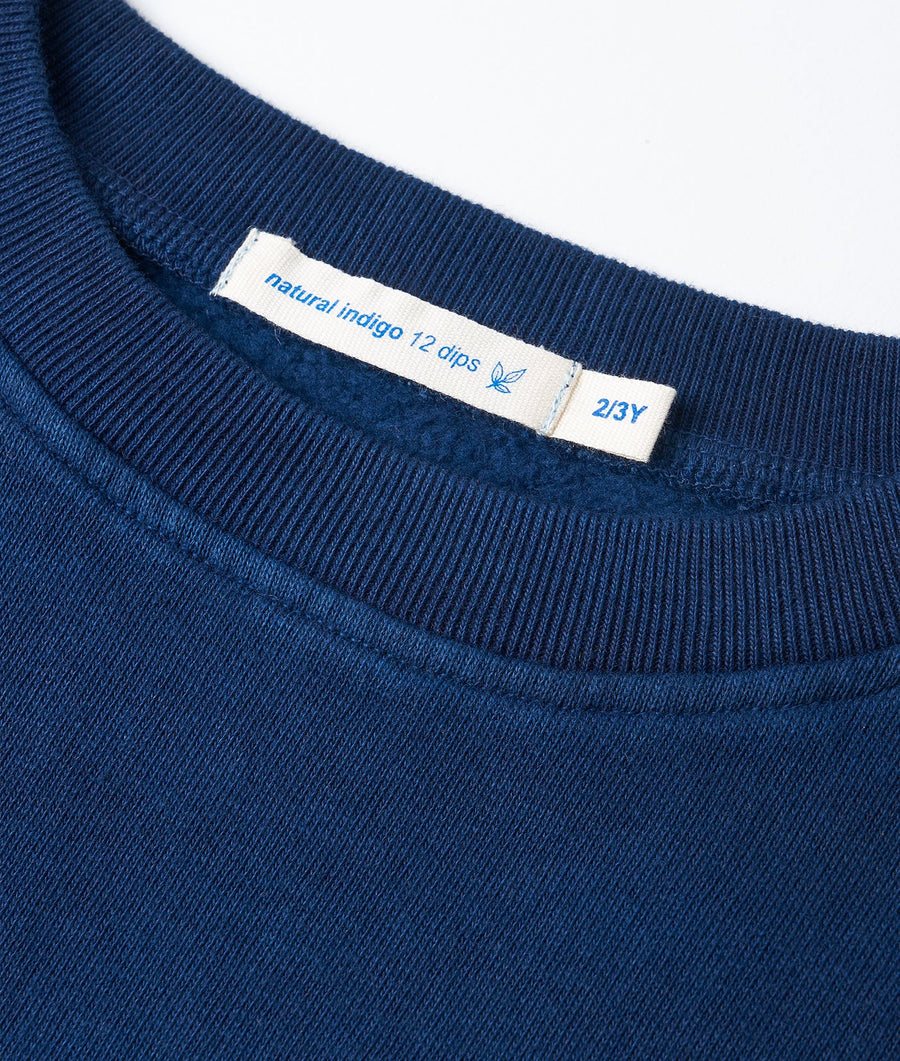 Close-up detail of a dark blue organic cotton t-shirt with a natural indigo dye label - Industry of All Nations