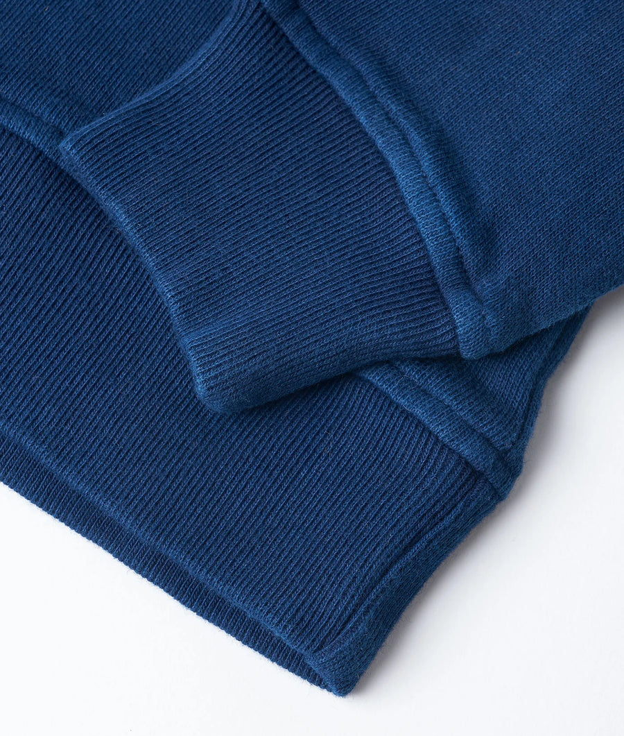 Close-up detail shot of a ribbed, navy blue knit sweater or jumper from Industry of All Nations.