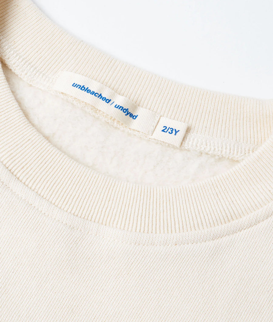 Detail shot of a cream-colored organic cotton ribbed t-shirt with size tag "2/3Y" - Industry of All Nations