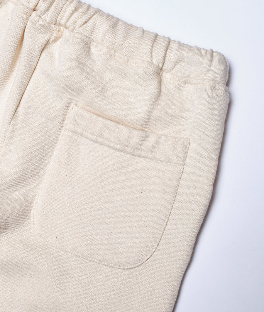 Closeup shot of a pair of beige cotton drawstring pants with a front pocket detail - Industry of All Nations