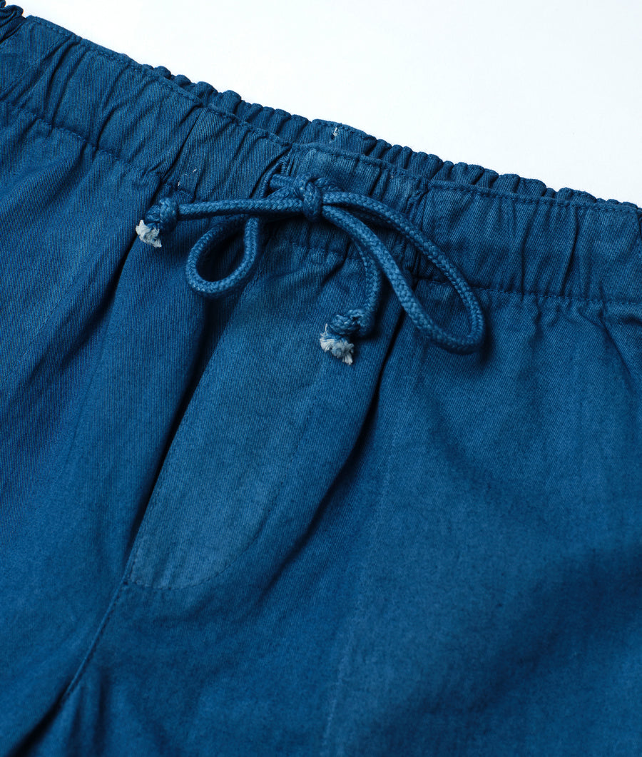 A closeup detail shot of a pair of dark blue, organic cotton drawstring pants from Industry of All Nations.