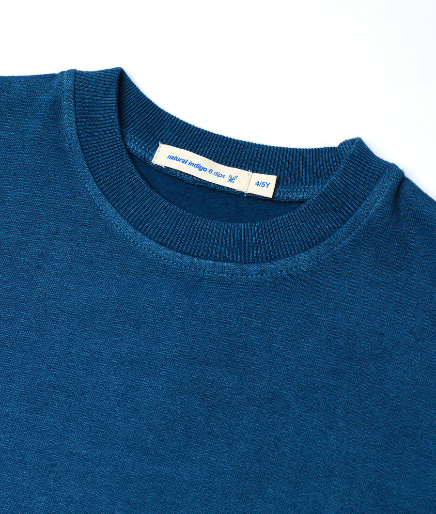 Close-up of a navy blue knit crewneck sweater with a natural indigo 8 clip label - Industry of All Nations