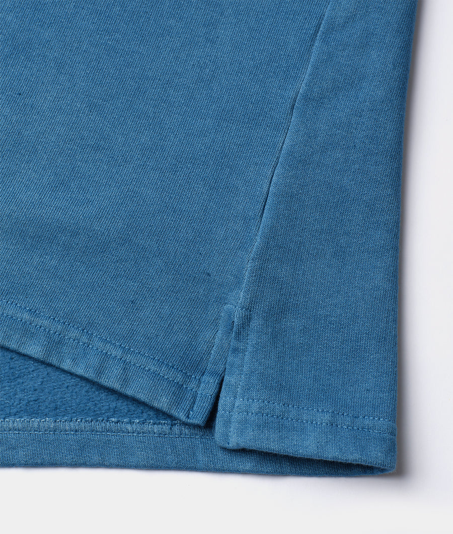 Close-up detail shot of a blue organic cotton t-shirt from Industry of All Nations.