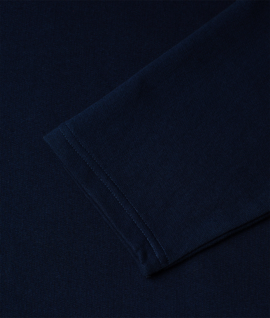 A close-up detail shot of a navy blue, organic cotton sweater from Industry of All Nations.