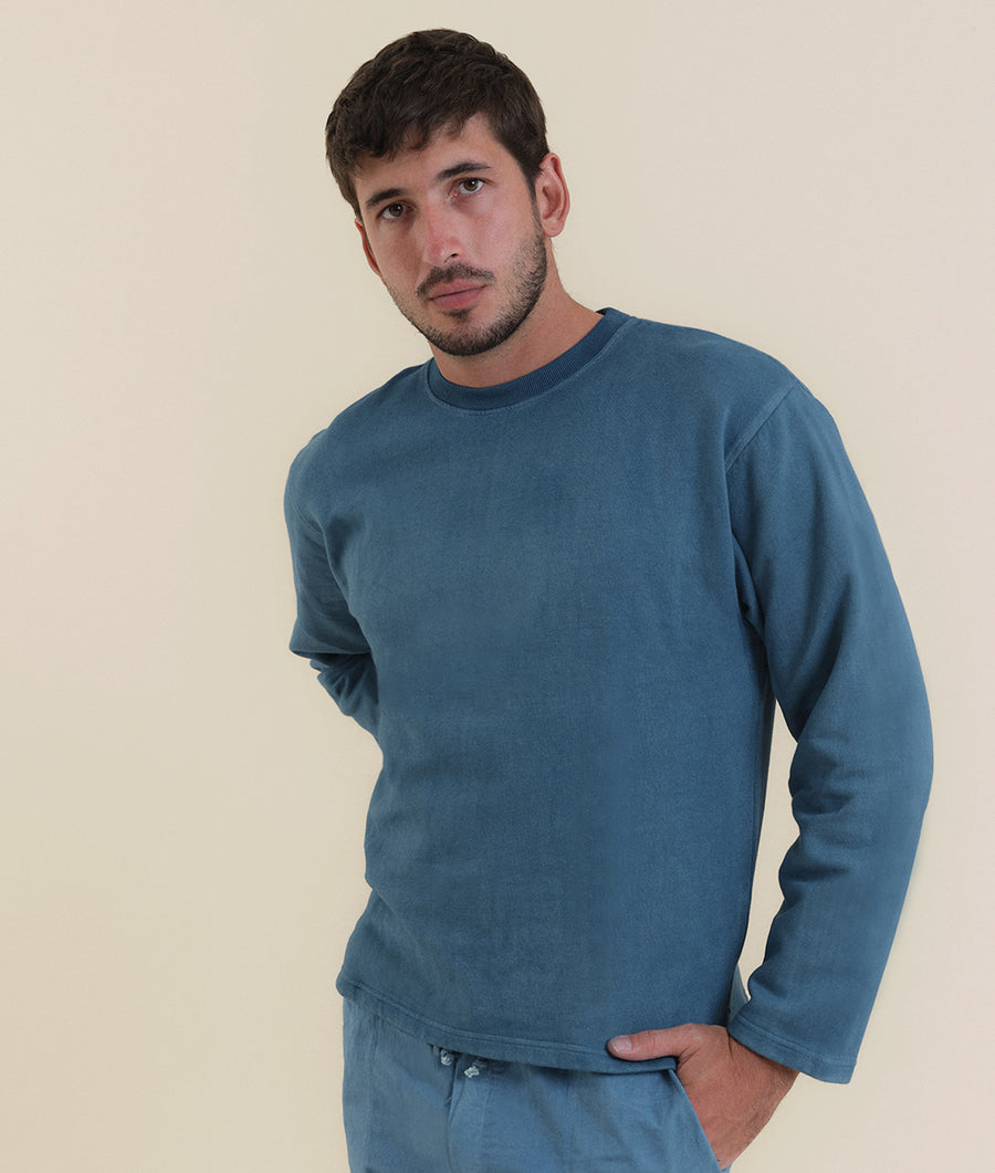 A man wearing a blue crewneck sweater - Industry of All Nations