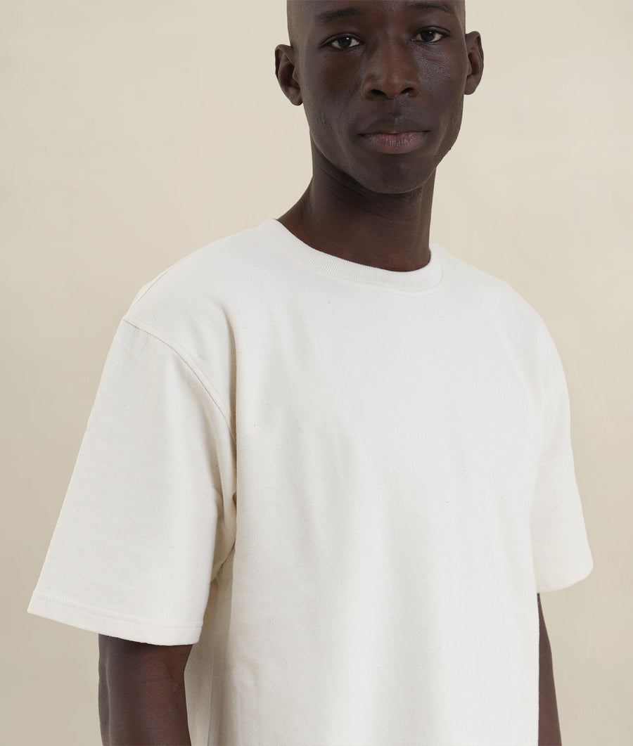 A Black male model wearing a simple white crew neck t-shirt in a studio setting - Industry of All Nations