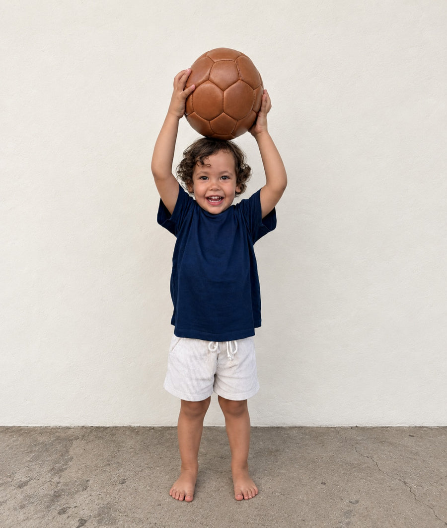 Toddler wearing an IOAN Kids Clean Crewneck T-Shirt in Indigo 12 and Kids Ponya Corduroy Shorts in Undyed.