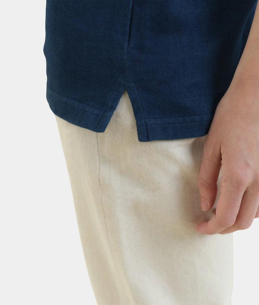 Close-up of a person wearing IOAN Indigo 12 Kung Fu T-Shit with undyed trousers, against a plain light background.