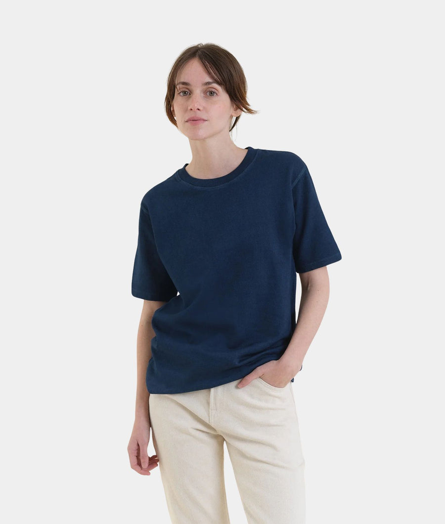 A woman modeling IOAN Kung Fu Sweatshirt in Indigo 12, paired with light beige trousers, against a plain light gray background.