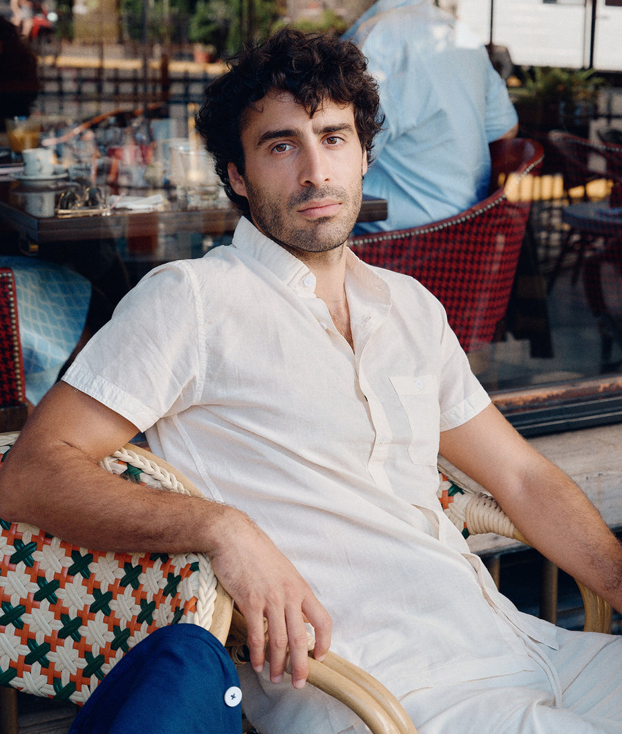 A man wearing a white button-down shirt is sitting in an outdoor seating area - Industry of All Nations