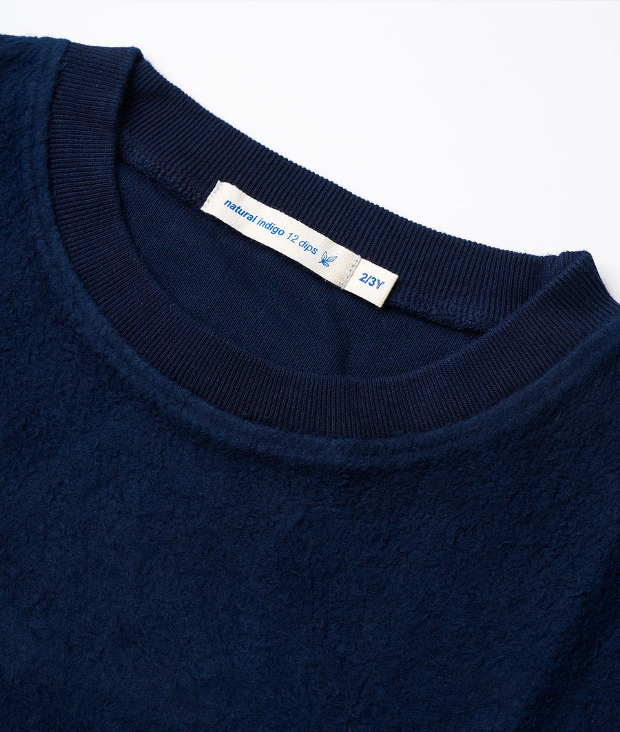 Navy blue organic cotton sweater with ribbed trim and natural indigo dye label, displayed in a flat lay - Industry of All Nations