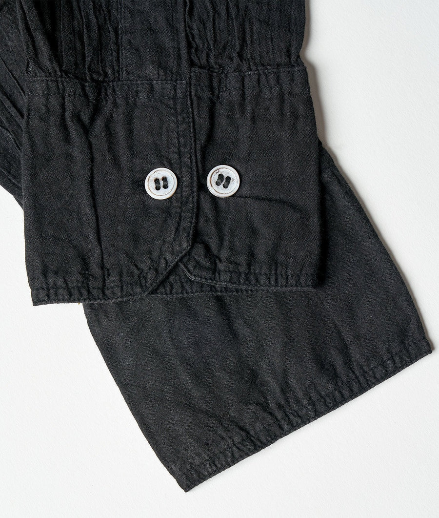 Detail shot of a black organic cotton jumpsuit with white button details - Industry of All Nations