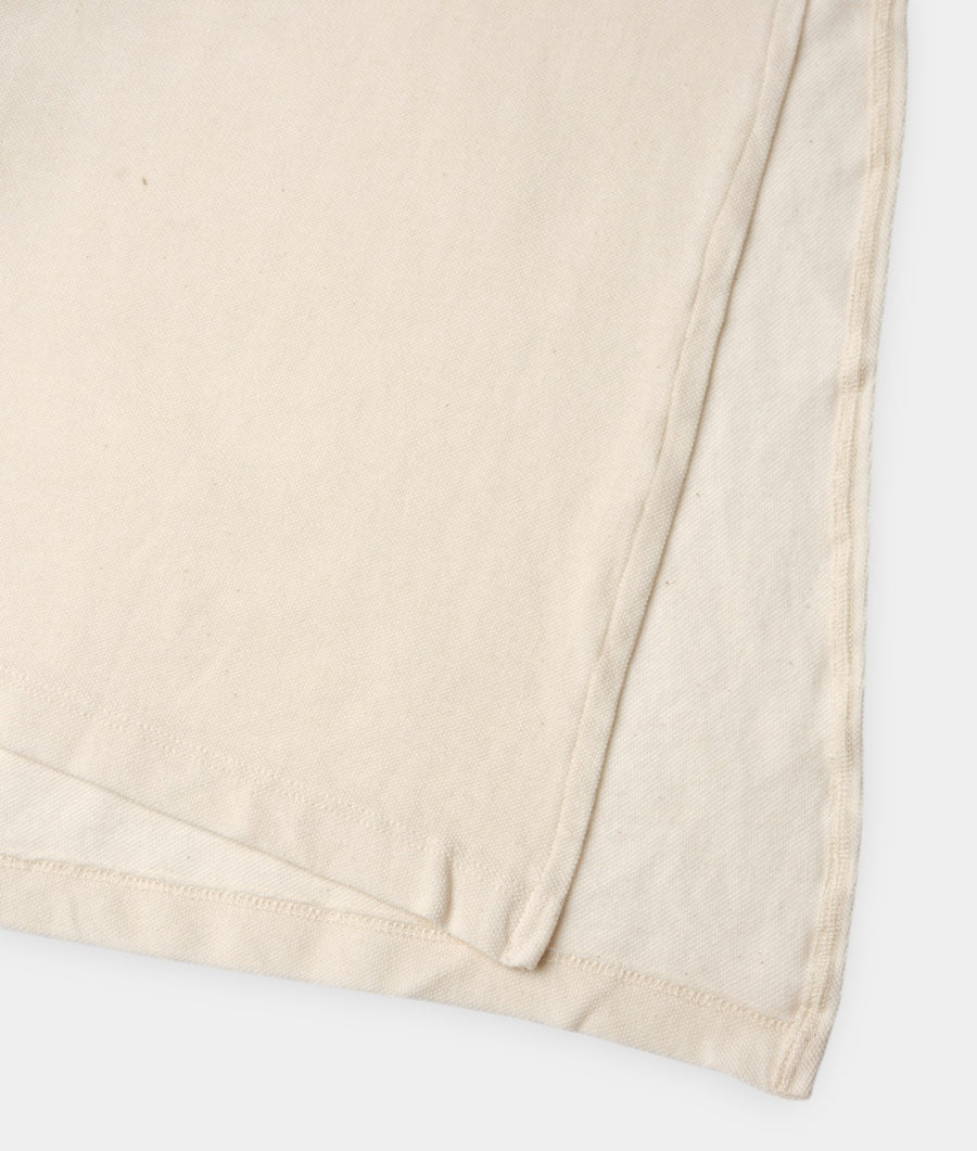A close-up detail shot of a cream-colored natural cotton fabric with a subtle ribbed texture - Industry of All Nations