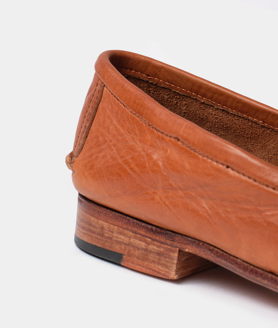 A close-up detail shot of a rust-colored leather boot with a unique silhouette and textured surface - Industry of All Nations