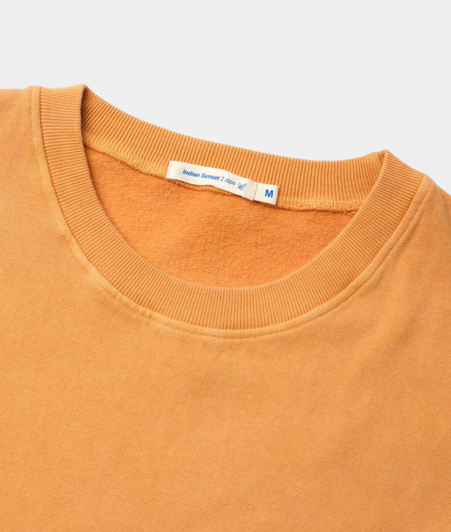 Close-up detail of an orange, ribbed sweater with "Indian Sunset 2 dips" label - Industry of All Nations