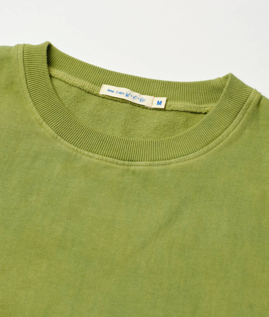 Green organic cotton sweatshirt with ribbed collar and hem, displayed as a close-up detail shot - Industry of All Nations