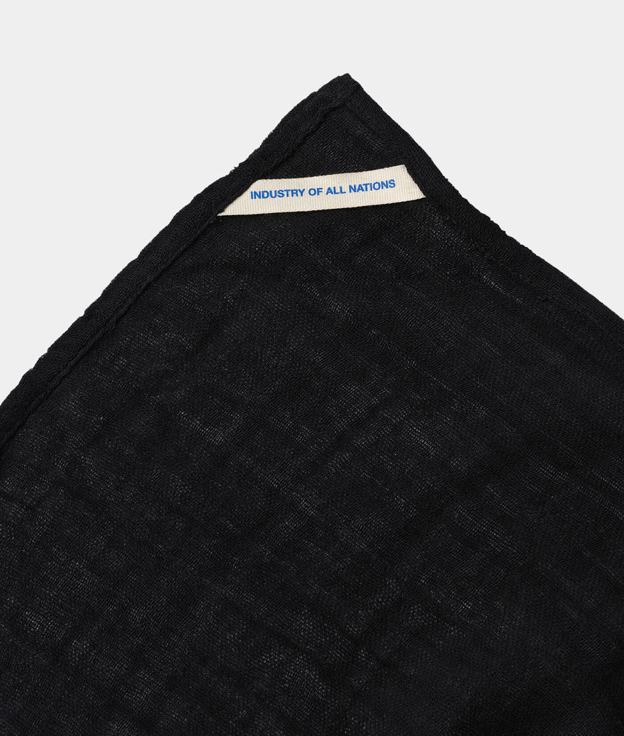 Black knitted scarf with "Industry of All Nations" label, flat lay on white background - Industry of All Nations