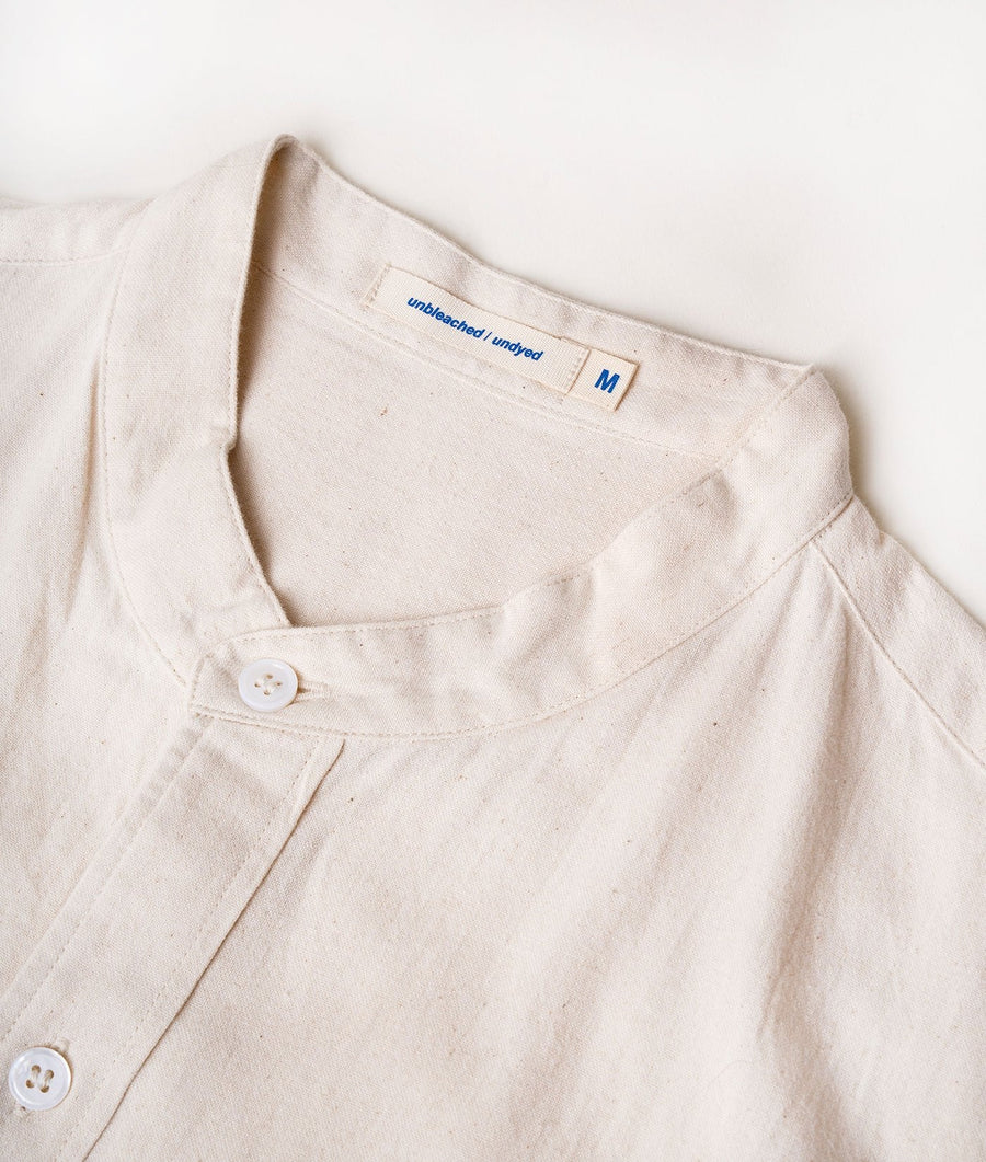 Close-up of a light-colored, unbleached, undyed shirt with a simple button-down collar and size label - Industry of All Nations