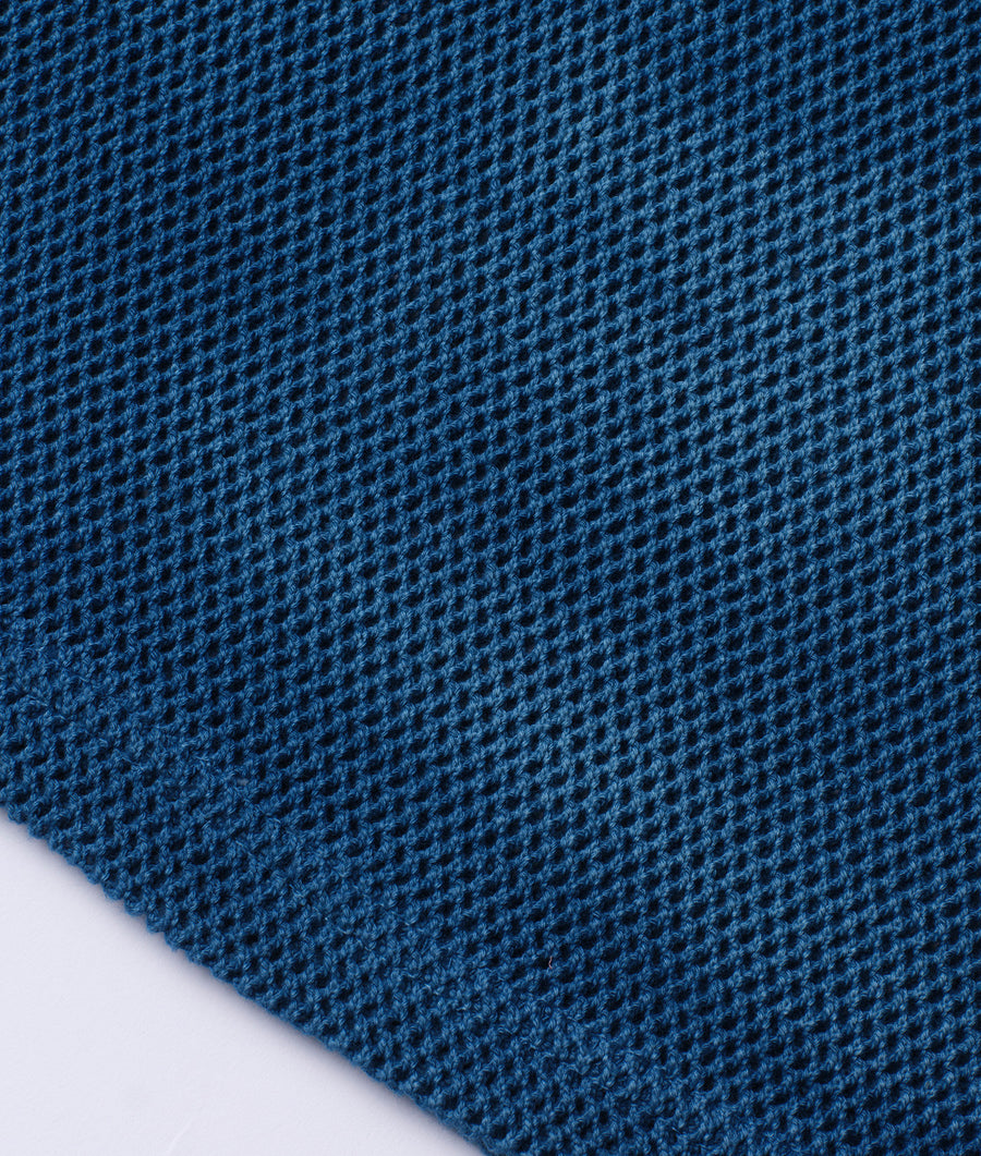 A close-up view of a blue knitted fabric texture with a diagonal pattern - Industry of All Nations