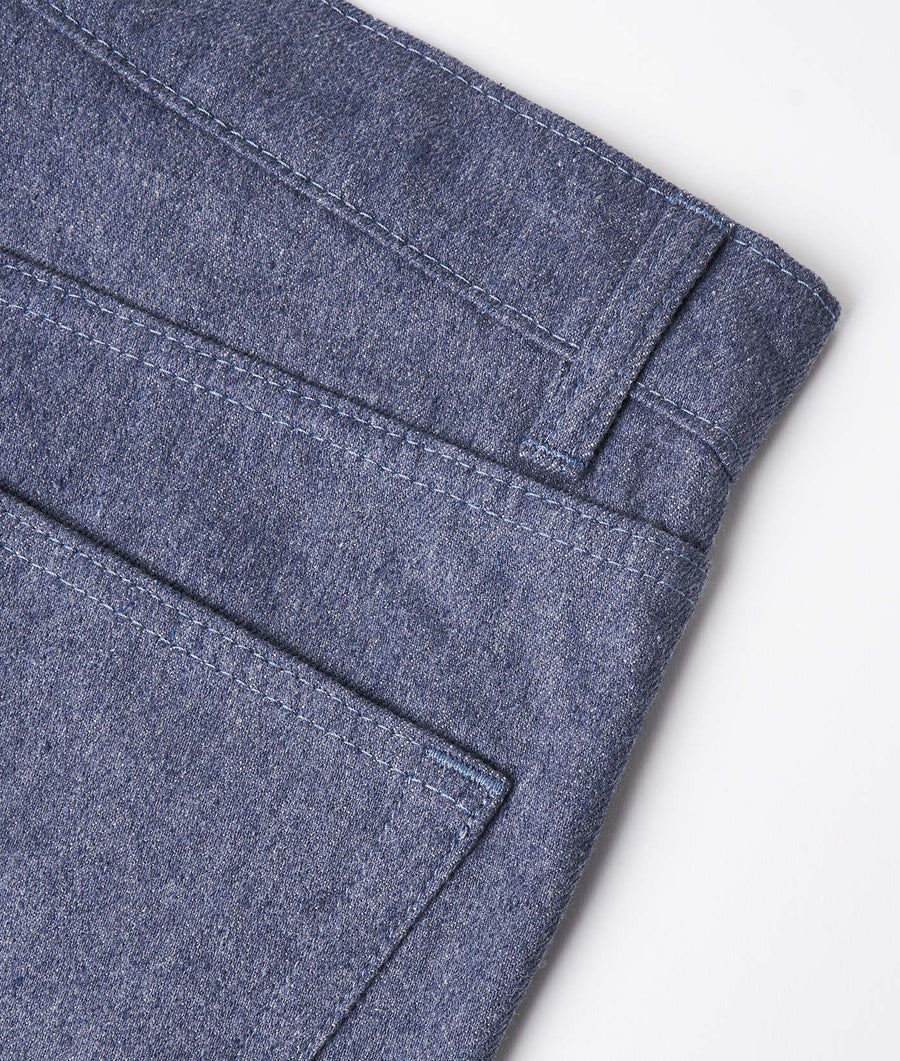 Close-up detail shot of a grey denim jeans fabric featuring visible stitches and distressed finish - Industry of All Nations