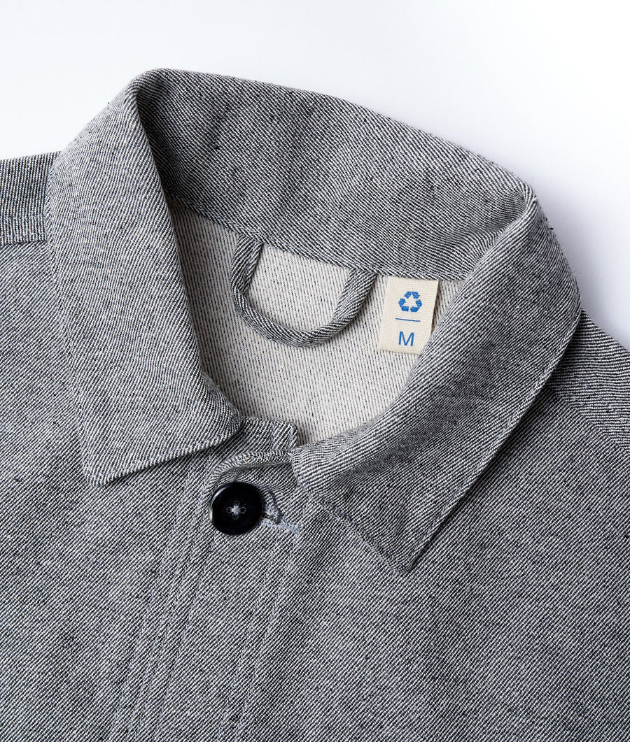 Flat lay detail shot of a gray chambray button-down shirt with a blue recycled logo tag - Industry of All Nations