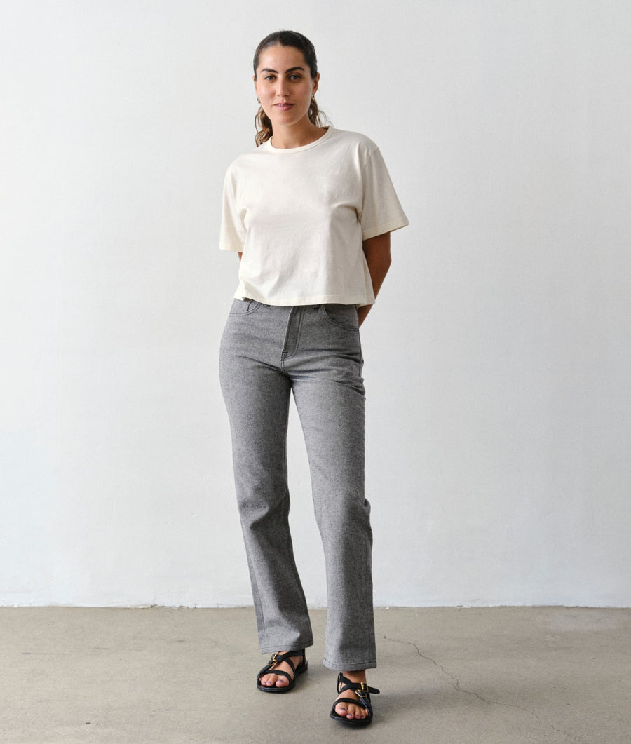 A woman models the IOAN New Jeans in Charcoal with an Undyed Cropped T-Shirt, shown from the front against a light gray studio background.