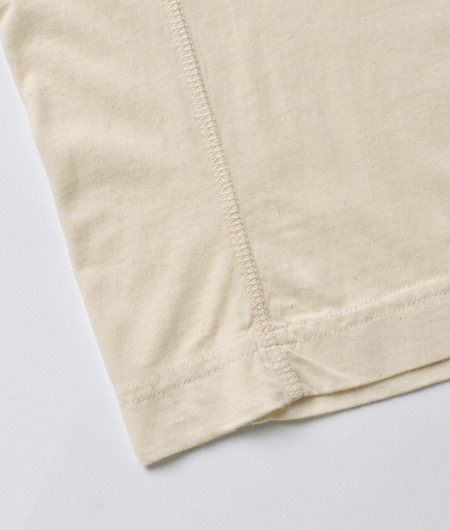 Detail shot of a beige organic cotton t-shirt displaying the stitching along the neckline - Industry of All Nations